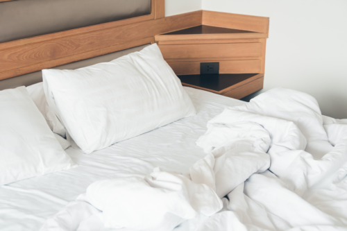 White pillow with rumpled bed