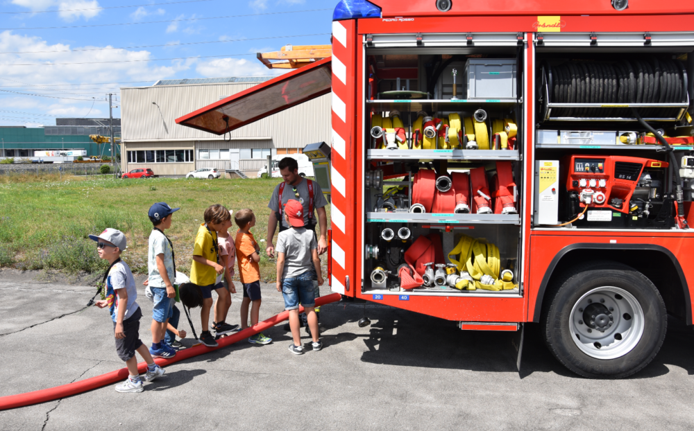 Kinder die vor einem Feuerwehrauto stehen.