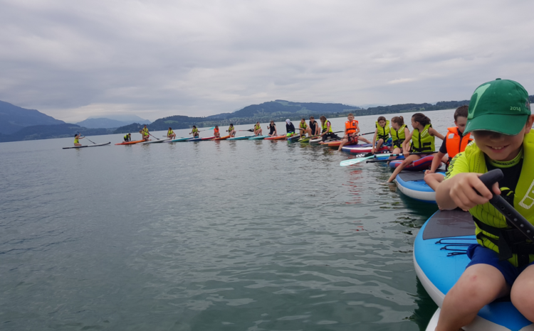 Eine Schlange von Kindern mit dem Standup Paddel auf dem Zugersee.