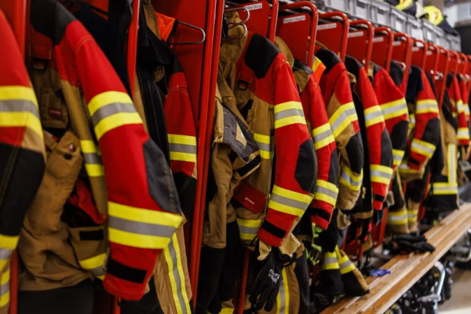Rote Feuerwehrjacken in der Garderobe, parat für schnelles Anziehen bei einem Notfall