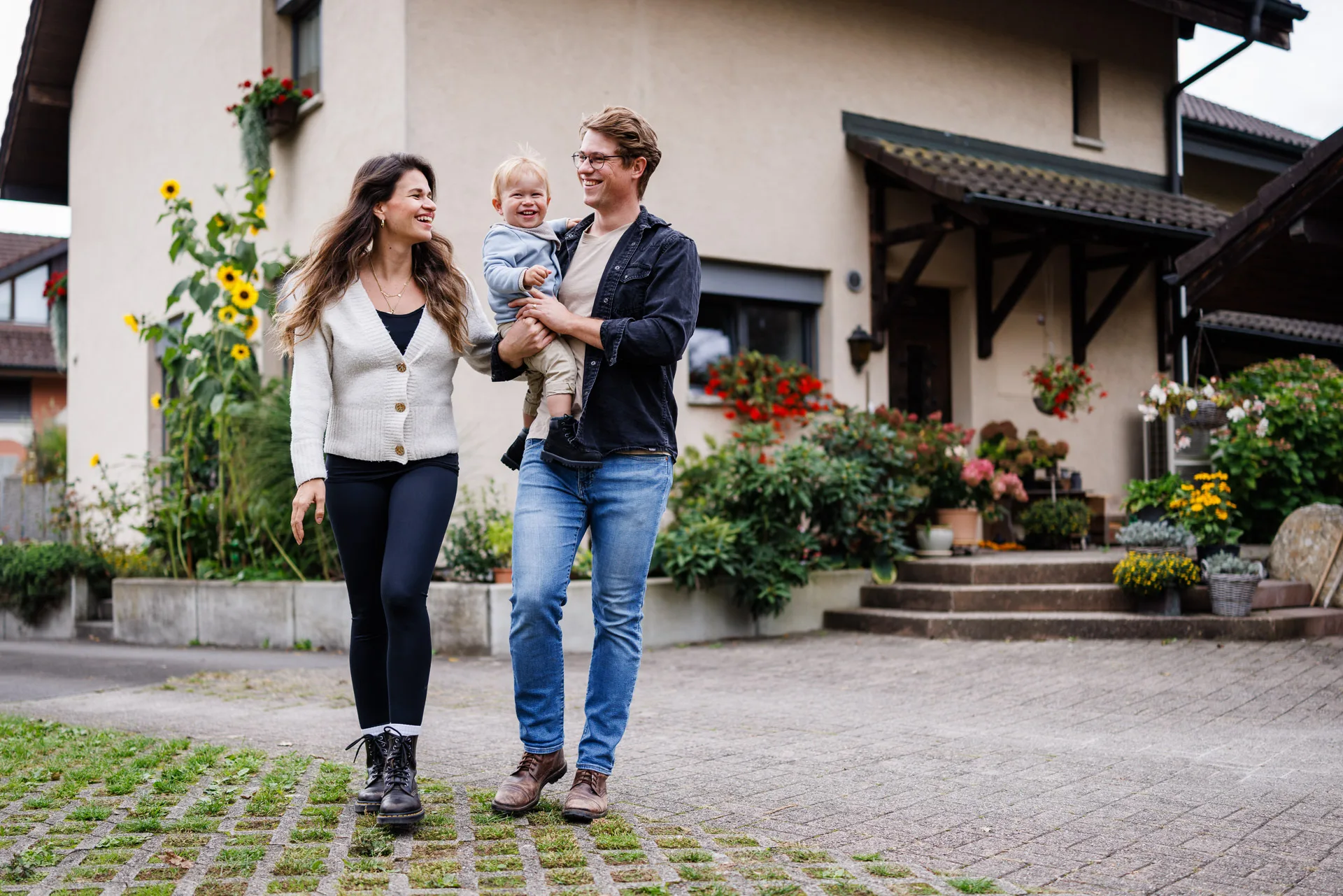 Eine junge Familie steht glücklich vor ihrem Eigenheim