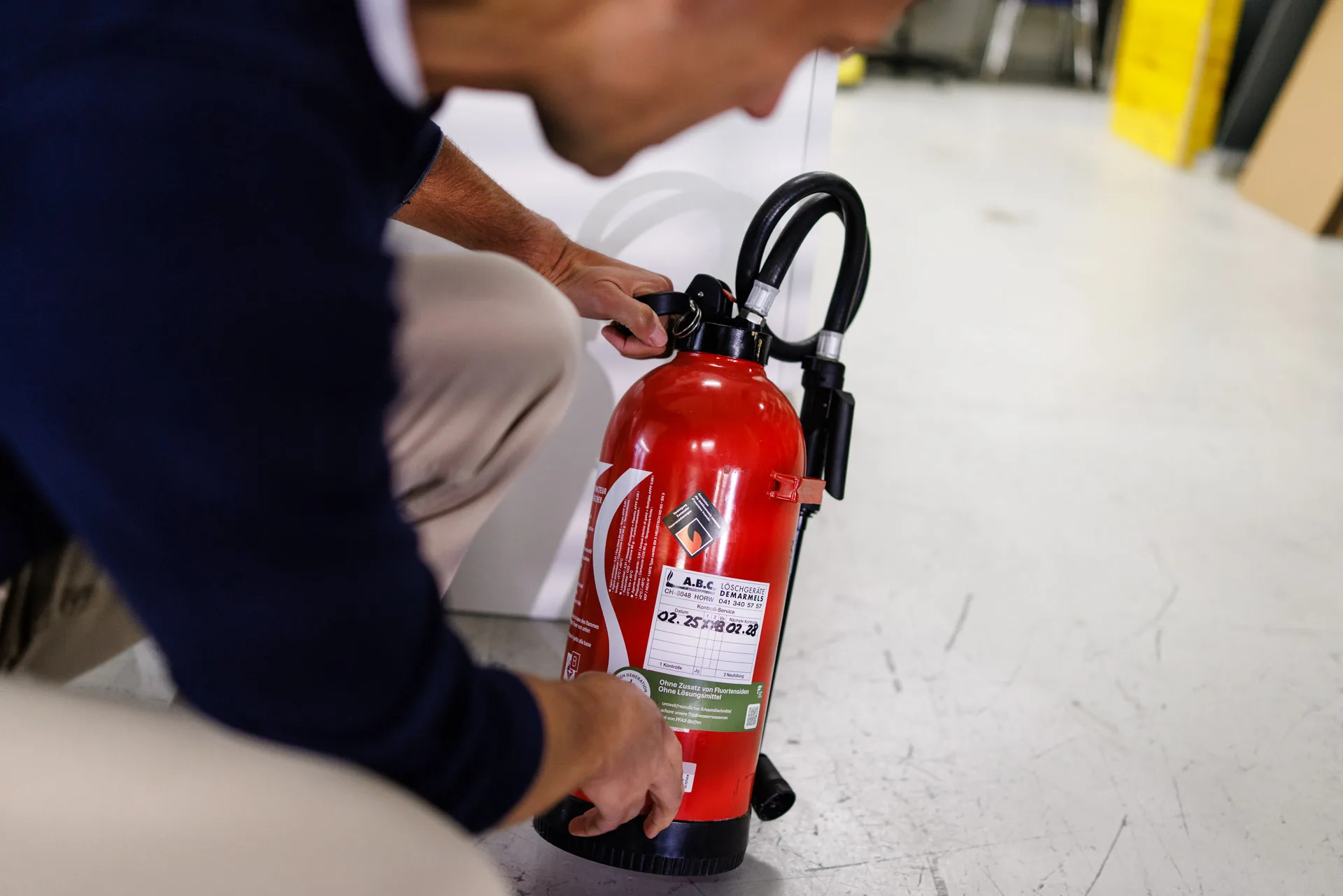 Mitarbeiter der GVZG überprüft einen Feuerlöscher