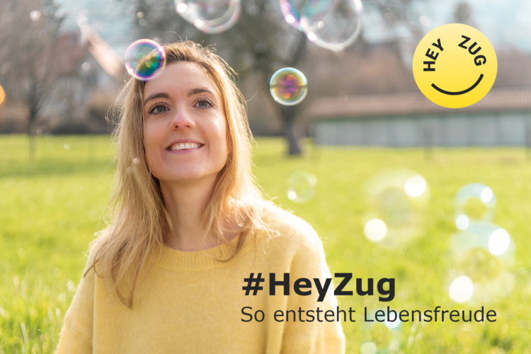blonde Frau bei Sonnenschein auf einem grünen Feld, umgeben von Seifenblasen