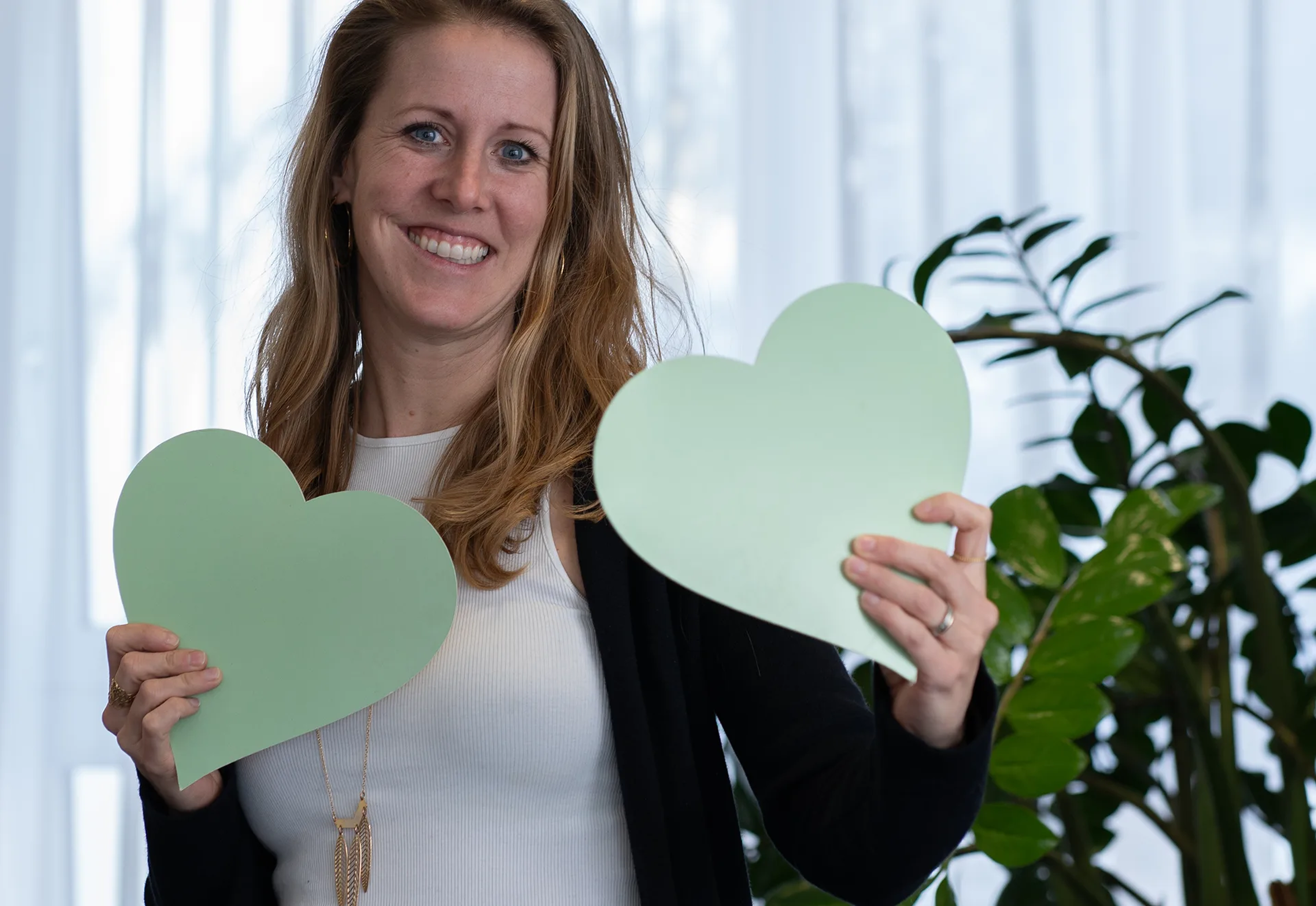 Involve Mitarbeiter-App Gebietsverkaufsleiterin Helen Habegger hält lächelnd zwei grünes Herz in der Hand