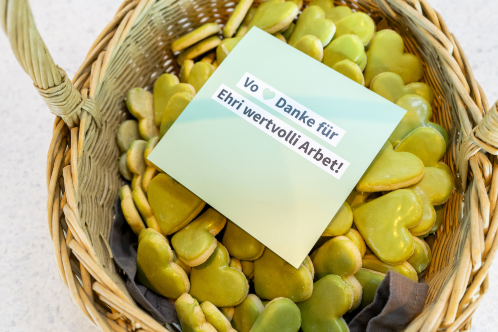 Ein Korb voller grüner Kekse in Herzform. Auf den Keksen liegt ein Involve-Prospekt.