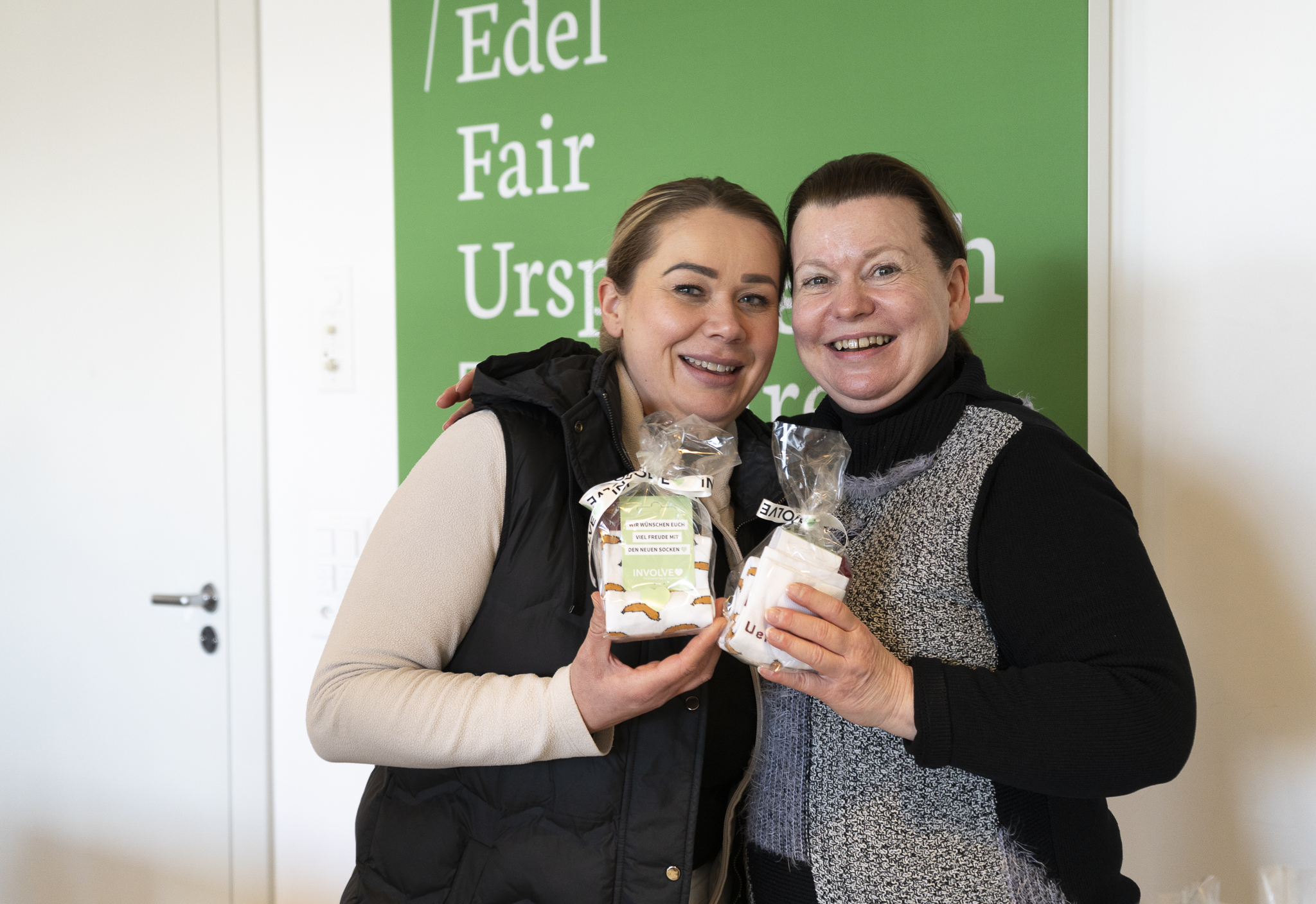 Zwei Mitarbeiterinnen der Ueli Hof AG mit dem Sockengeschenk von Involve in den Händen.