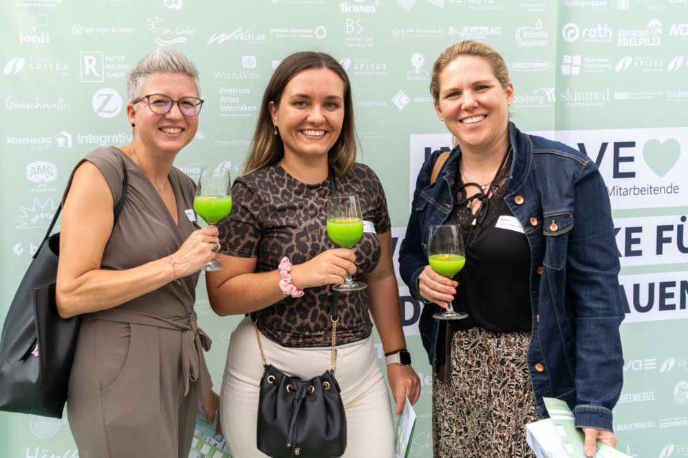 Drei Involve-Kundinnen stehen vor der Logowand bei der Involve Night 2025 im Burgrain.