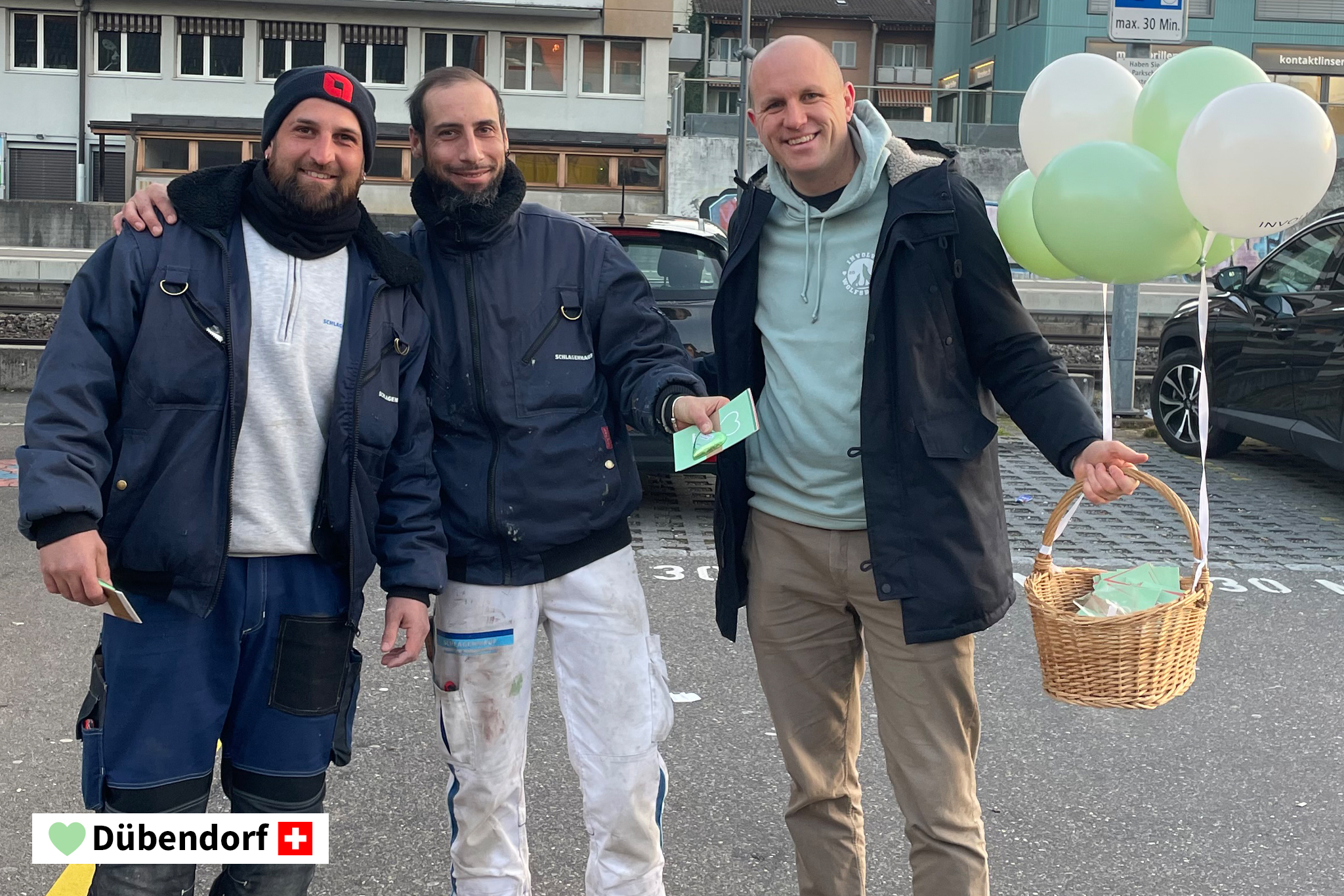 René Kaiser, Geschäftsführer und Inhaber Involve AG, mit zwei Passanten in Dübendorf. Sie stehen lächelnd beisammen und René Kaiser hält einen Korb mit Luftballonen in der Hand.