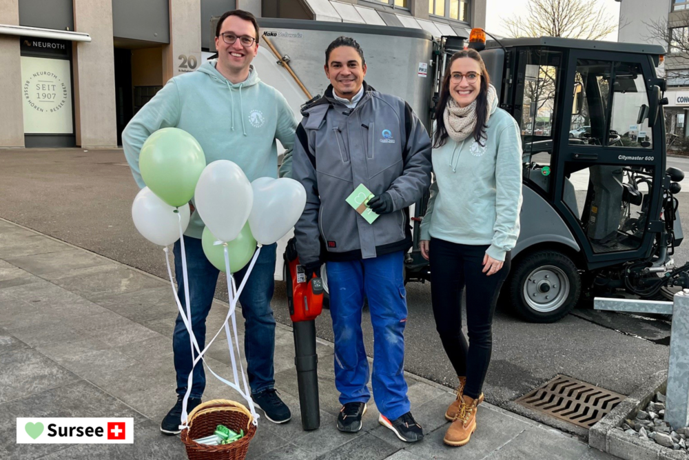Zwei Mitarbeitende der Involve AG mit einem Passanten in Sursee. Sie lachen in die Kamera und haben einen mit Ballonen geschmückten Korb dabei.