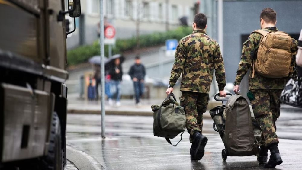 Zwei Angehörige des Schweizer Militärs laufen auf einem Gehweg.