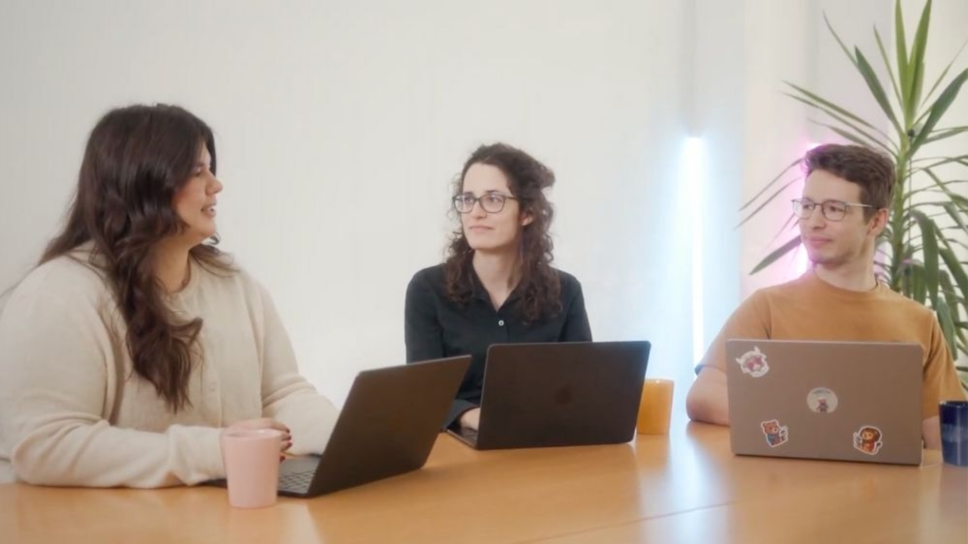 Drei Mitarbeiter:innen von ipt arbeiten gemeinsam an einem Tisch.