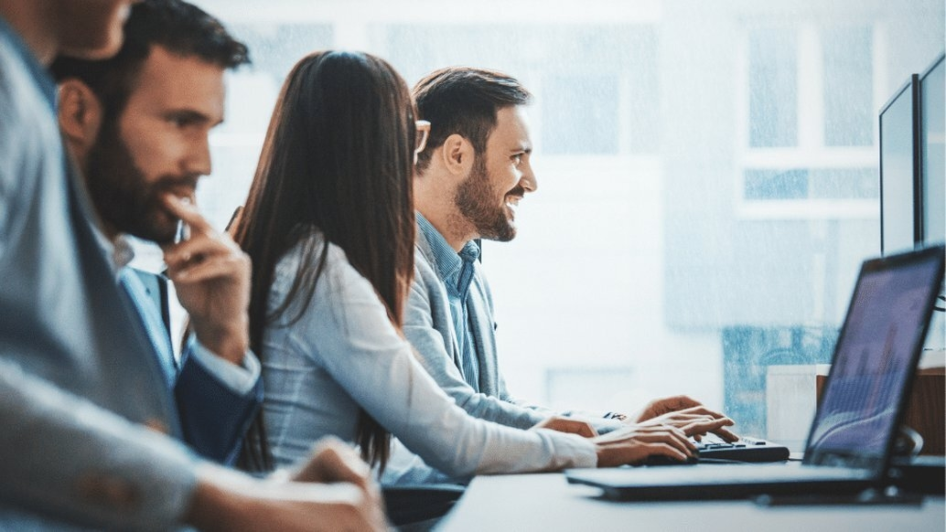 Mehrere Personen arbeiten an Laptops und Computer in einem Büro.