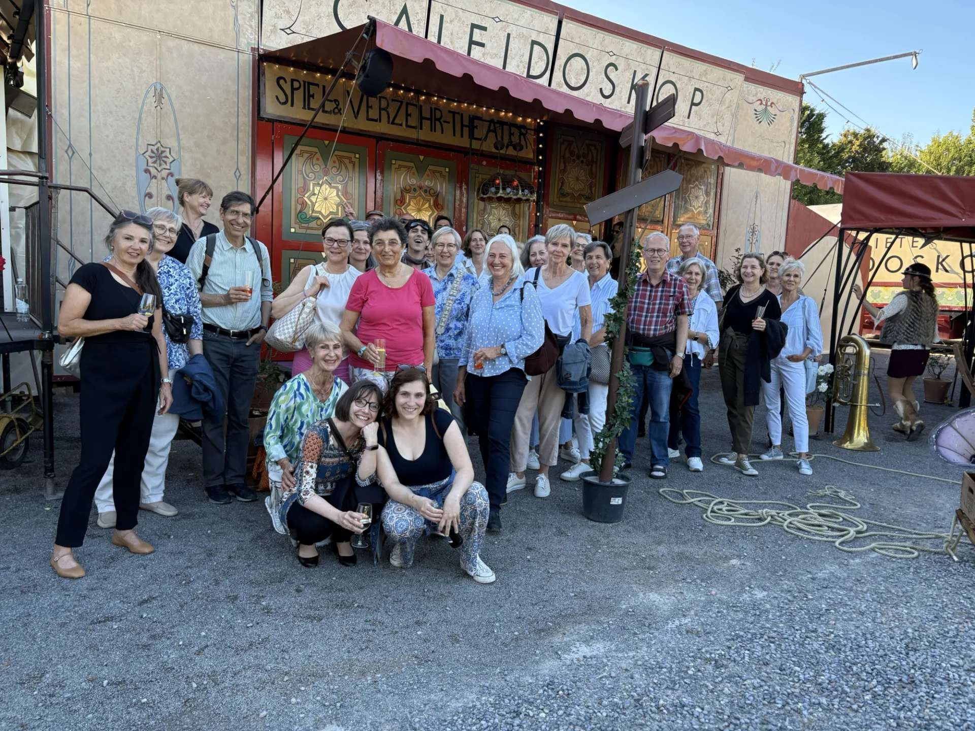 Gruppe von Frauen und Männern lachen in die Kamera vor einem bunten Hintergrund.