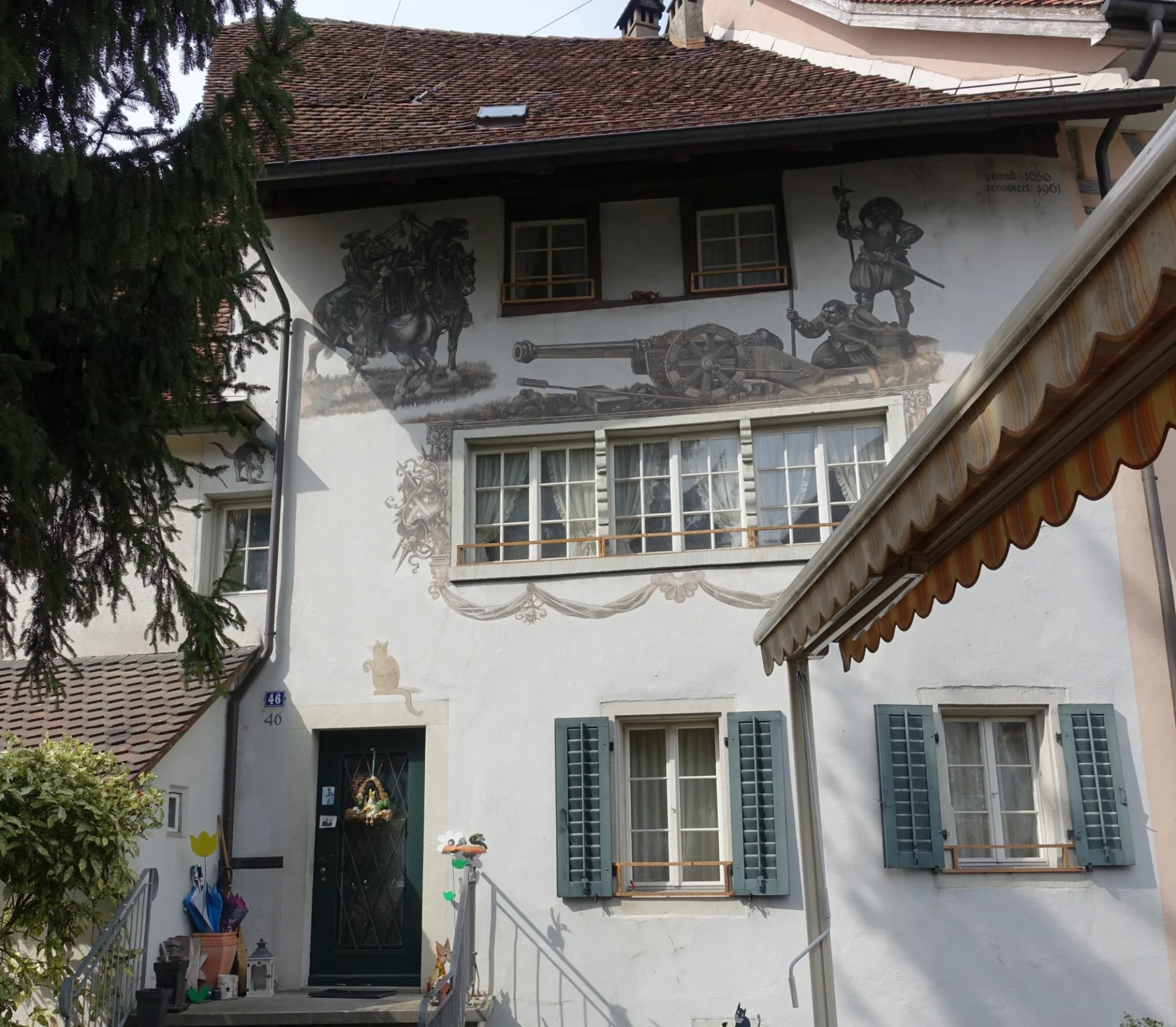 Die Fassade mit Malereien von Kanonen und Hellerbardieren vor der Renovation.