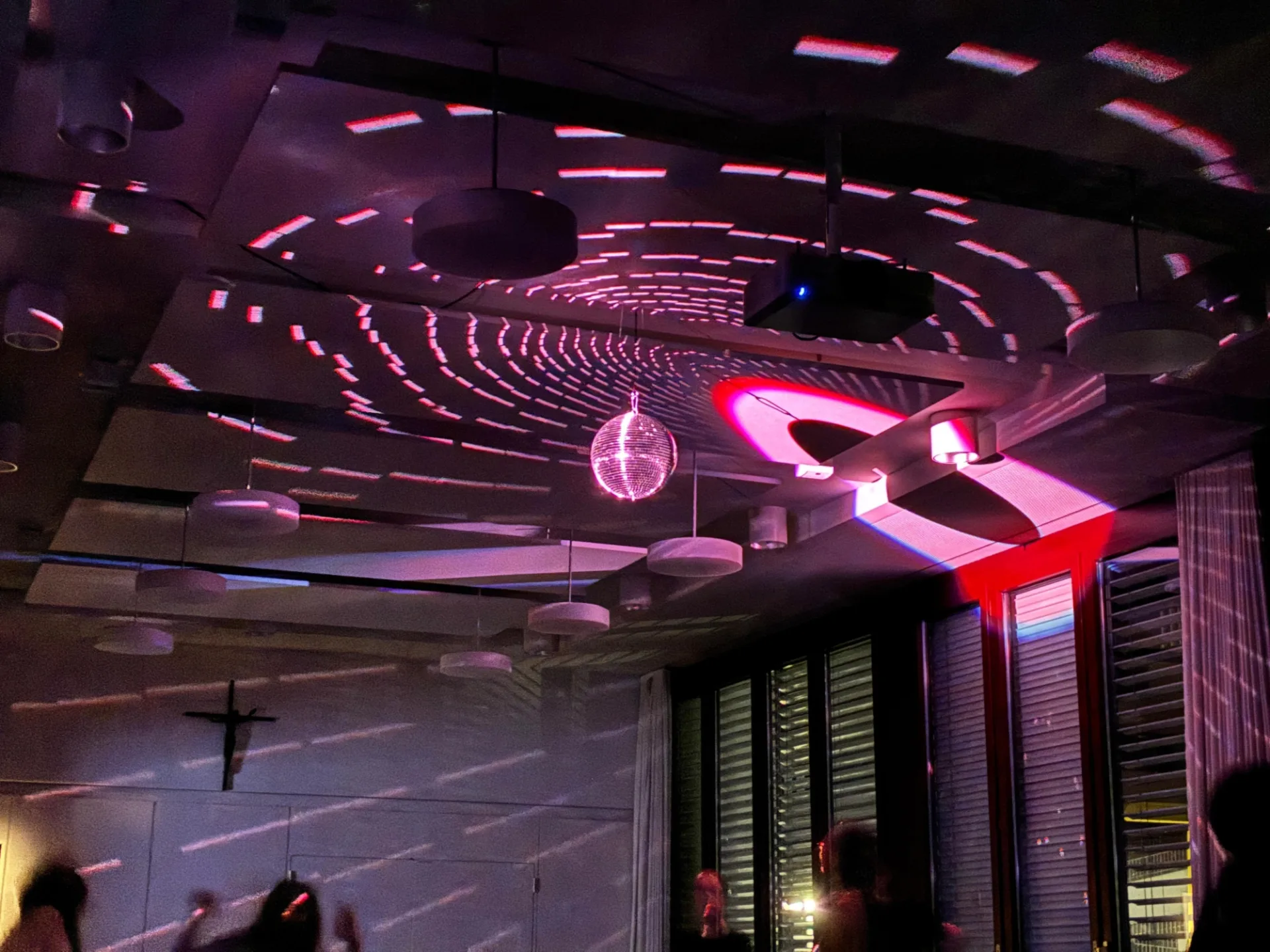 Discokugel mit violetten Lichtmuster an einer dunklen Decke.