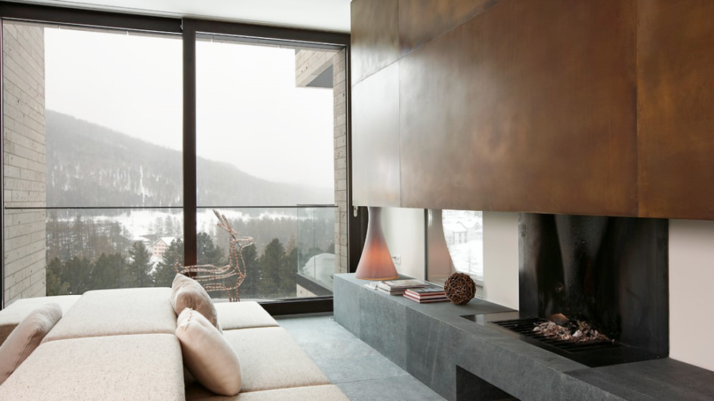 Modernes Wandcheminée in Messing mit einer Steinbank aus Stein.