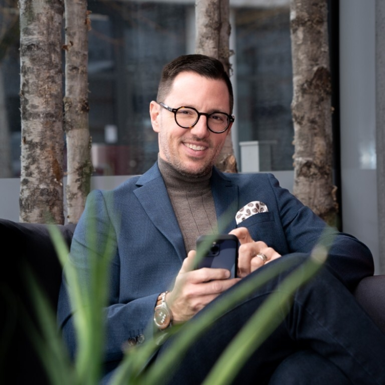 Potrait von Patrick Mollet, ein Mann mit Brille und blau-grauem Blazer