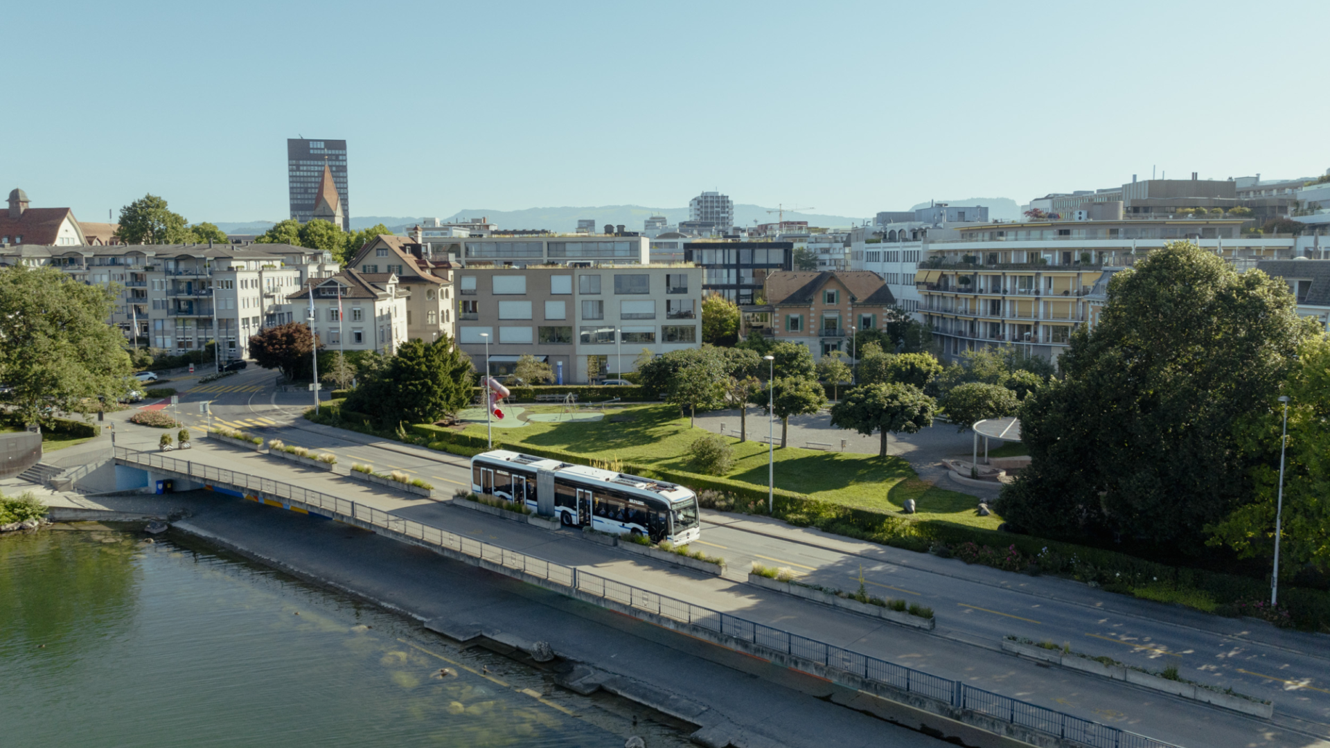 Blick auf die Häuser von Zug mit Zugersee und Bus auf der Strasse.