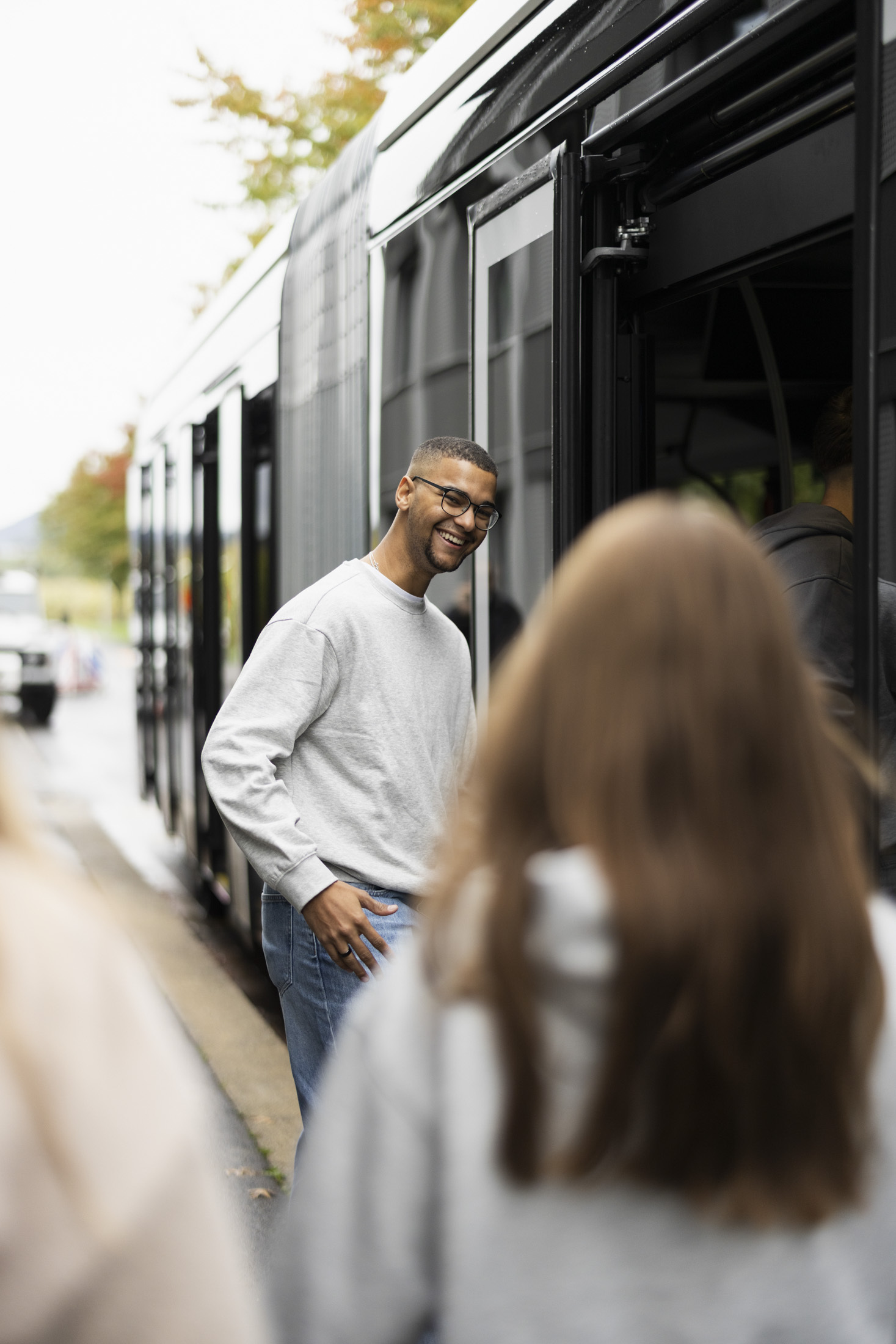 Junger Mann wartet beim Einsteigen in den ZVB Shuttle Bus auf seine Kolleginnen an der Haltestelle
