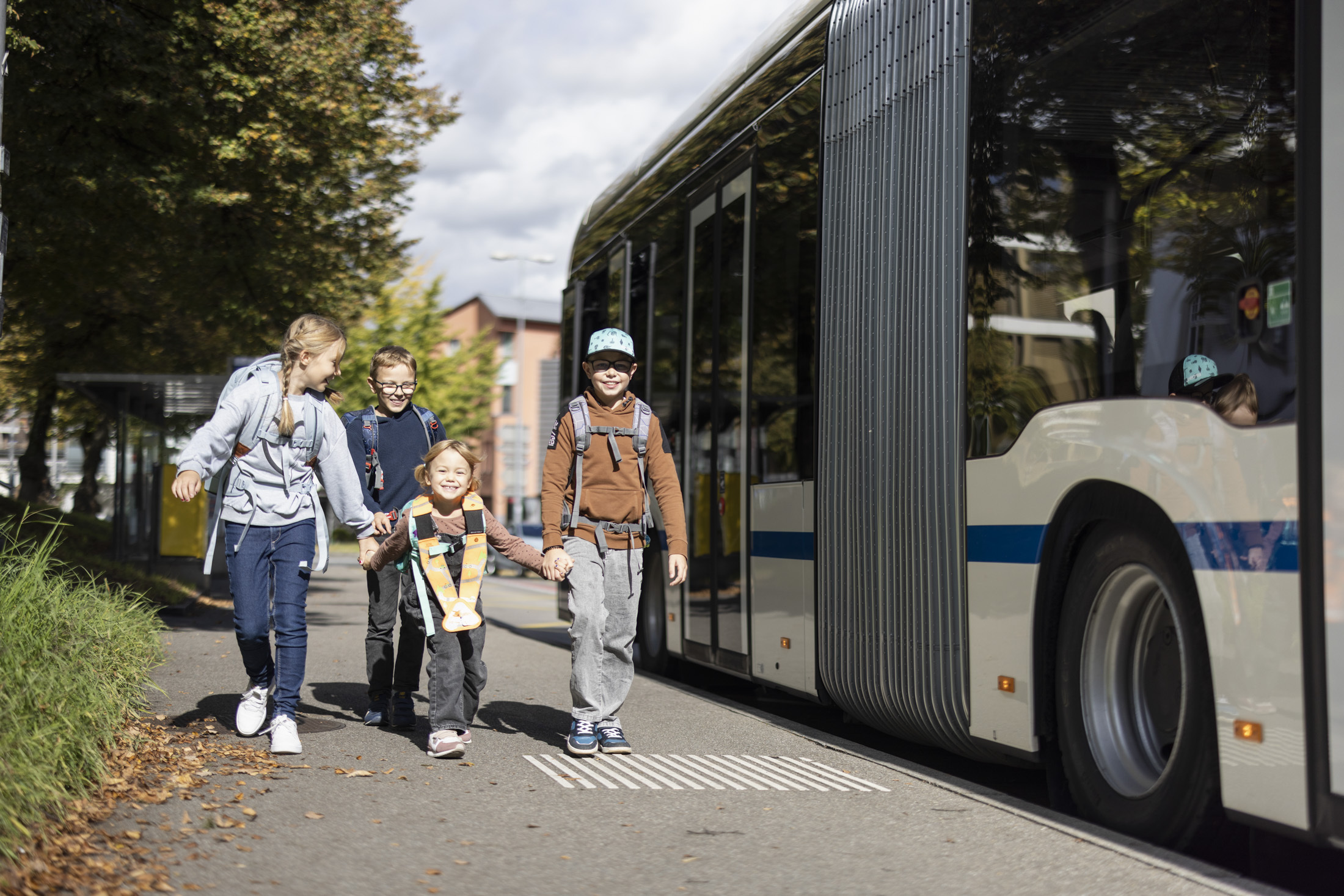Schulkinder laufen neben dem Bus und bestreiten ihren Schulweg