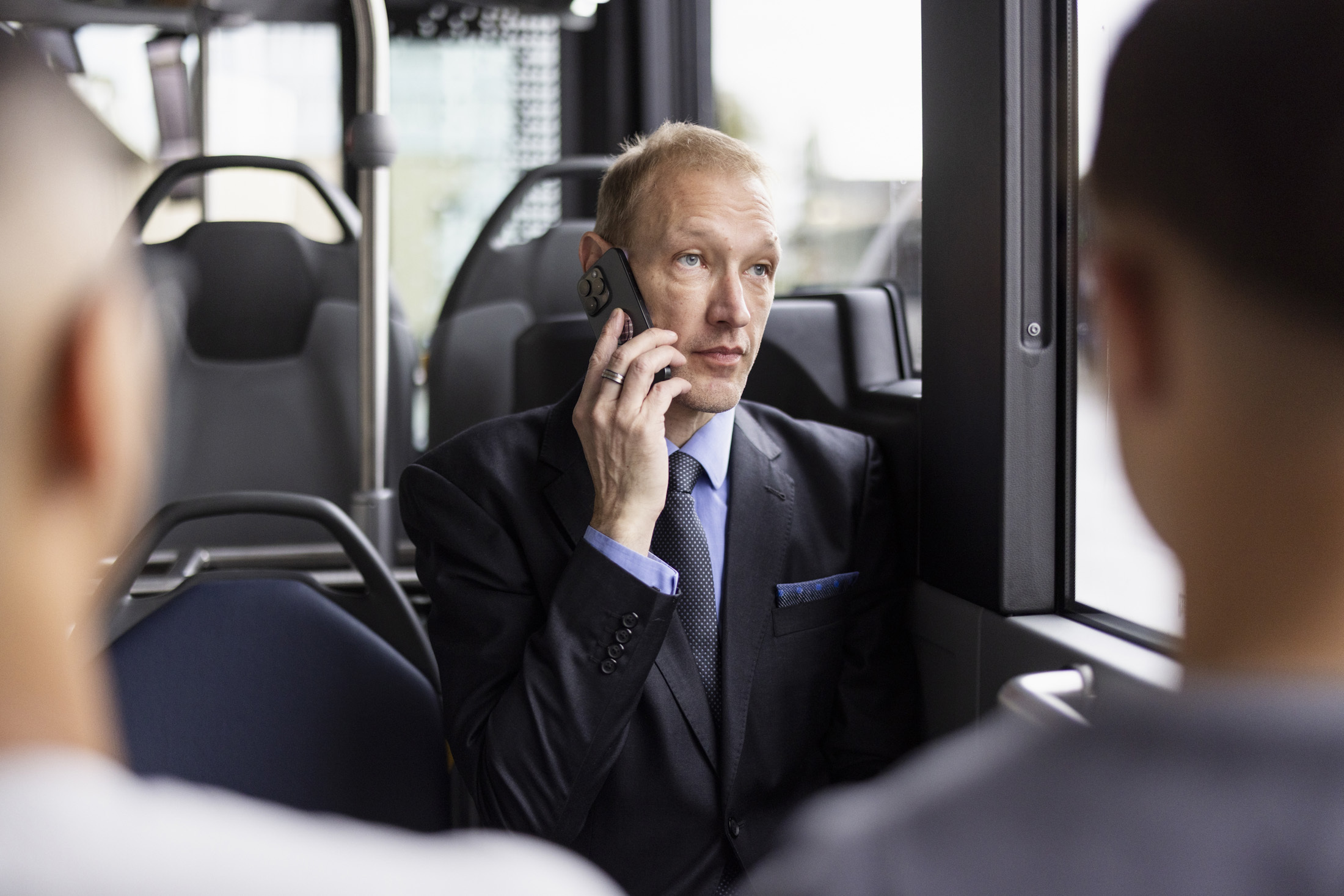 Business-Men am Smartphone sitzt im ZVB Bus auf dem Weg zur Arbeit