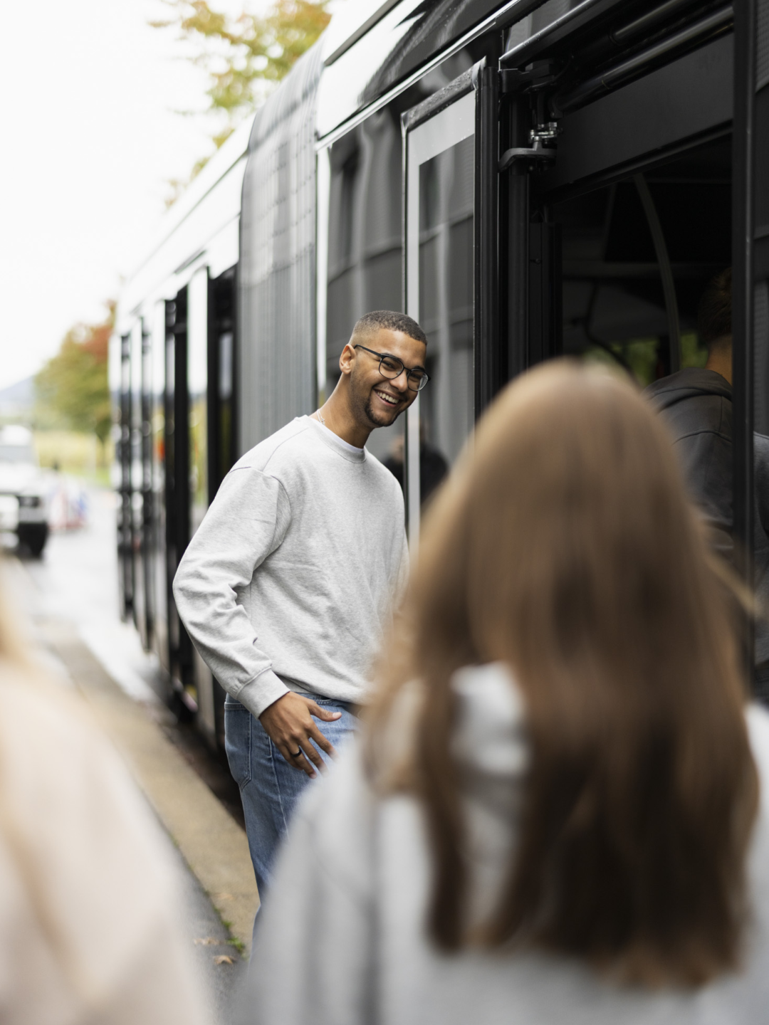 Junger Mann wartet beim Einsteigen in den ZVB Shuttle Bus auf seine Kolleginnen an der Haltestelle