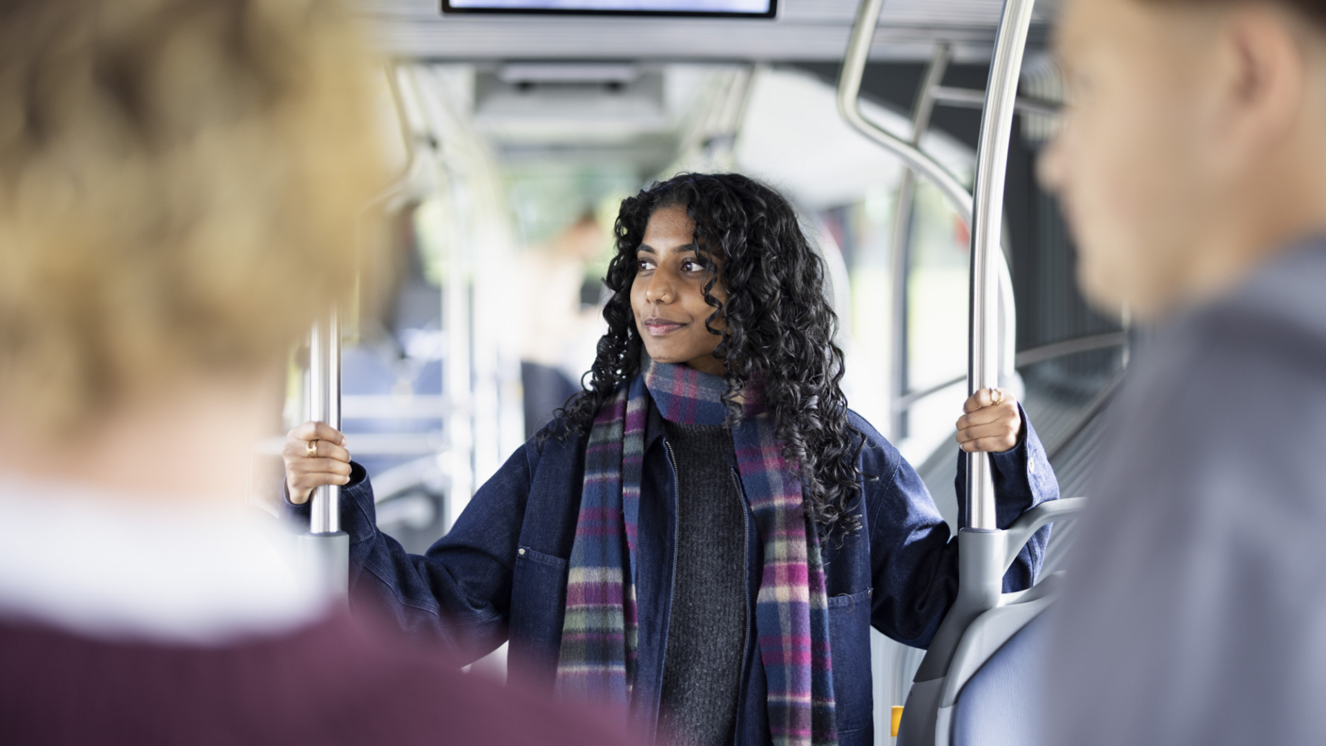 Junge Frau fährt stehend im Bus der Zugerland Verkehrsbetriebe AG und hält sich an Haltestange aus Chrom fest